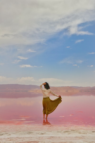 During the day, wearing a white shirt and a yellow skirt woman stood on the brown on the beach
